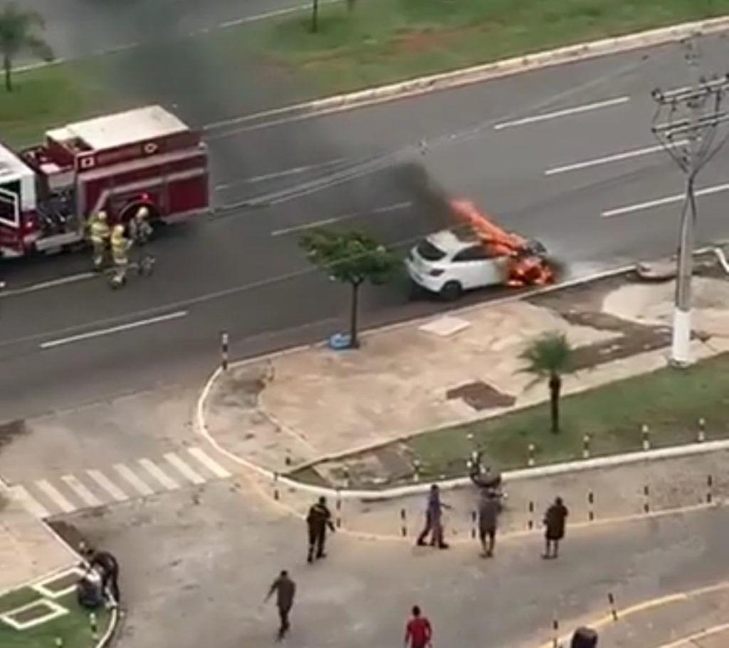 Carro pegando fogo e bombeiros próximos
